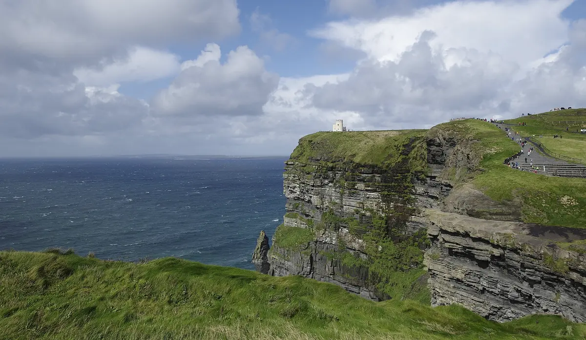 Le Cliffs of Moher: pareti di roccia stratificata coperte d'erba sull'oceano, con la O'Brien's Tower sul ciglio